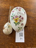 Large and small ceramic eggs on wood background, showing scale