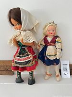 Both dolls standing side by side showing full costumes and relative heights