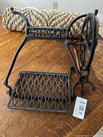 Full view of cast iron Singer treadle base side showing logo, pedal and wheel