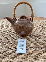Overall view of brown speckled stoneware teapot with bamboo handle and lid
