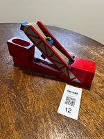 Side view of red wooden LEGO conveyor belt toy on table