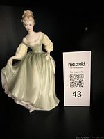 Front view of Royal Doulton Fair Lady figurine next to lot card