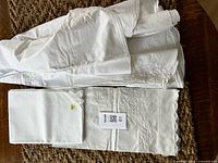 Folded white linens showing two tablecloths and napkins