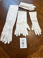 All four pairs of white gloves laid out showing different lengths and styles