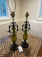 Pair of green glass and metal table lamps on table, full view