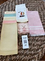 Stack of eight assorted vintage linen fingertip towels showing colors and designs