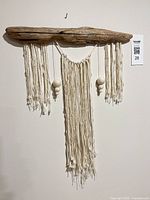 Full view of driftwood wall hanging with hanging fibers and wool beads