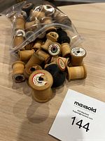 Bag of assorted wooden thread spools with some labels visible