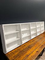 Full view of white wooden wall shelf on table