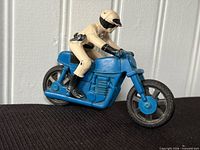Full left side view of blue rubber motorcycle and beige rider