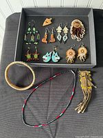 Overview of tray containing earrings, pendant, necklace, pouch, bracelet