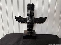 Front view of carved wooden thunderbird totem pole on base