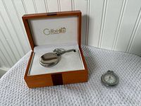 Colibri pocket watch with chain in wood box beside New Swiss pocket watch