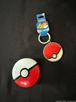 Front view of both items: plastic Poké Ball toy and metal key ring