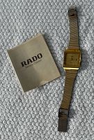 Front view of watch and booklet on textured surface