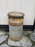 Front view of galvanized milk can with lid showing yellow band and embossed lettering