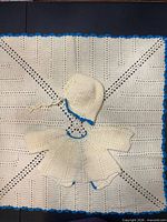 White blanket with blue trim, matching coat and hat displayed