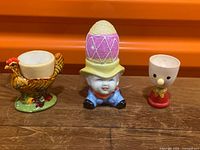 front view of three egg cups: chicken, cowboy, Noddy