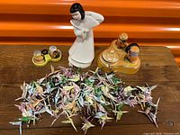 Overview of figurine, salt & pepper set and pile of origami cranes on table