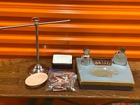All items arranged on table showing towel stand, soap dishes, curlers, scale and pewter bottles