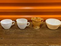 Full group view: two Moonglow cups, Peach Luster creamer, white swirl casserole
