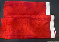 Folded red lily print fabric showing pattern and selvage