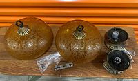 Two amber crackle glass globes with hardware laid out