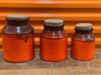 Front view of all three orange pottery canisters with cork lids