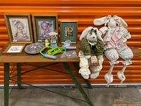 Table with entire assortment: plush bunnies, framed pictures, dish, rope, figurines
