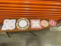 Five assorted crocheted doilies displayed on ironing board