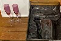 Pair of pink champagne flutes beside boxed clear set