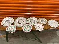 Eight crochet doilies laid out on wooden table
