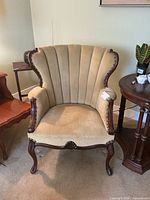 Front view of beige suede-like upholstered armchair with carved wood frame
