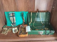 Full lot view with jewelry roll, open green metal box, wooden tray holding jewelry