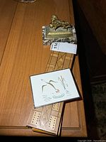 Lot overview showing brass lion sculpture on marble base, two cribbage boards, small signed print