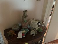 Group view of frog figurines, plush toys, wooden guiro, candle holder on table