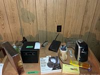 Overview of lot on table showing safe, earbuds, router, remotes, mug with pens, Post-its, pencil pack and sharpener