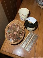Overview showing wicker basket of pennies, black jar, plastic can and coin set
