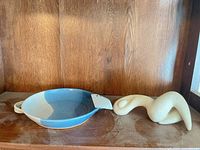 Blue and cream pottery dish and off-white abstract figure on wooden shelf