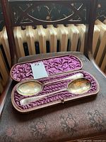 Open case showing two silver plate serving spoons with gilt bowls