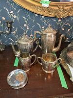 Full view of silver-plated coffee pot, teapot, creamer, sugar bowl and stack of coasters
