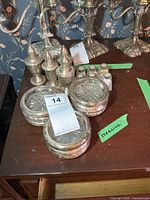 Group shot of weighted sterling shakers, six mini shakers and nine sterling-rim glass coasters