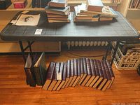 Full view of black plastic folding table with books on top (contents not included)