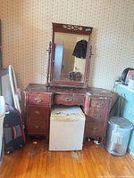 Front view of wooden vanity with mirror showing overall design and finish wear