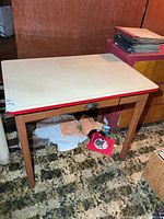 Full view of wooden table with enamel top and drawer closed