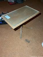 Full view of wood accent table with glass inset top and tripod metal base