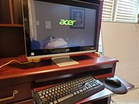 Acer all-in-one computer displaying boot logo with keyboard and mouse on desk