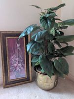 Artificial philodendron beside framed floral print