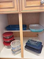 cabinet view showing entire lot: enamel pan, ceramic dish, glass storage containers with lids, glass pans