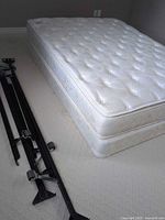 Mattress on box spring with metal frame pieces alongside
